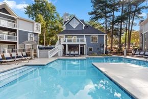 Raleigh apartment for rent - A swimming pool in front of a house with a deck and lounge chairs.