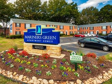 Newport News apartment for rent - A sign for Mariners Green Apartment Homes sits in front of a building.