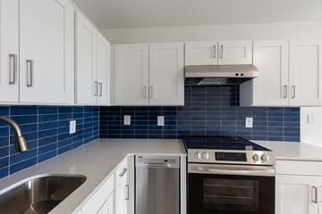 Charlotte apartment for rent - A kitchen with white cabinets and a blue tile backsplash.