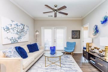 Raleigh apartment for rent - A living room with a beige couch, a blue chair, and a painting on the wall.