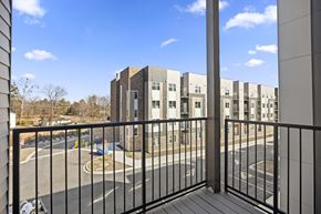 Charlotte apartment for rent - A view from a balcony overlooking a parking lot and apartment buildings.