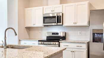 A kitchen with a sink, microwave, oven, and cabinets.