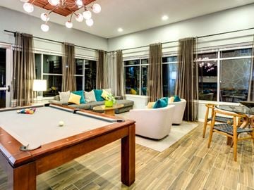 Newport News apartment for rent - A pool table is in the middle of a living room with a couch and a chair.