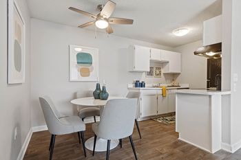 A dining room and kitchen with white cabinets and a ceiling fan