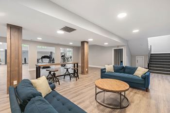 A living room with couches and a bar and a staircase