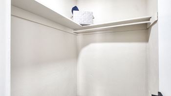 A small closet with a white wall and a shelf
