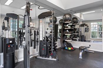A gym with a variety of equipment including a weight bench, a leg press machine, and a cable machine.