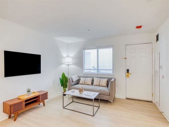 Rockville apartment for rent - A living room with a grey couch, a wooden coffee table, and a flat screen TV mounted on the wall.