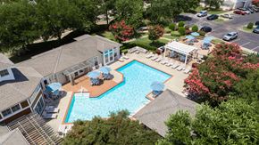 Virginia Beach apartment for rent - A large swimming pool surrounded by trees and a building.