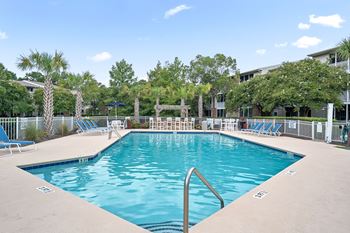 A large swimming pool surrounded by palm trees and lounge chairs.