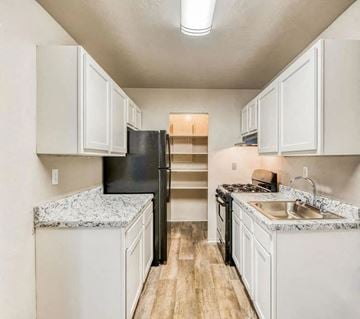 Norfolk apartment for rent - a kitchen with white cabinets and a black refrigerator
