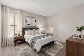 Raleigh apartment for rent - A bedroom with a large bed and a wooden nightstand.