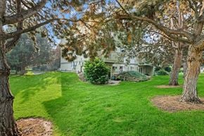 Boise apartment for rent - A house is surrounded by a green lawn and trees.