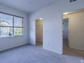 Reno apartment for rent - A spacious room with a window, carpeted floor, and two doors.