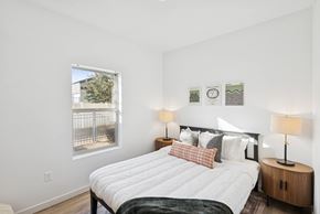 Boise apartment for rent - A bedroom with a large bed and a window overlooking a fence.