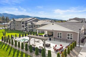 Post Falls apartment for rent - A large house with a pool and a mountain in the background at Woodland Meadows Apartments, Post Falls, ID