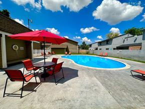 Boise apartment for rent - A pool area with a table and chairs and a red umbrella.