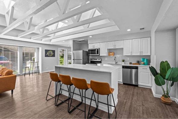 Boise apartment for rent - A modern kitchen with white cabinets and a large island with four chairs.