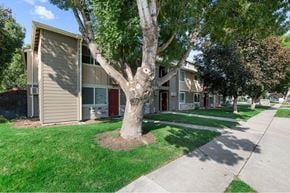 Boise apartment for rent - A tree in front of a building with a red door.