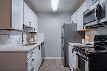 Boise apartment for rent - A kitchen with white cabinets and black appliances.