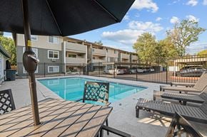 Boise apartment for rent - A pool surrounded by wooden deck chairs and umbrellas.