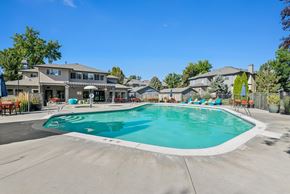 Boise apartment for rent - A large outdoor swimming pool surrounded by lounge chairs and umbrellas.