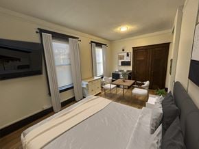 Detroit apartment for rent - A bedroom with a large bed and a small kitchenette.