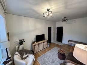 Detroit apartment for rent - A living room with a white couch, a television, and a wooden cabinet.