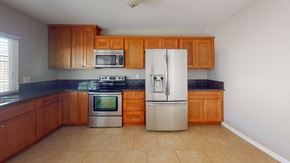 Vacaville apartment for rent - A kitchen with a white refrigerator, black countertops, and wooden cabinets.