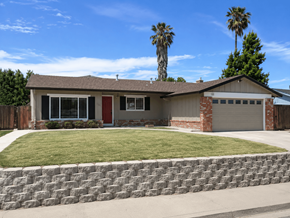 Pittsburg apartment for rent - A house with a red door and a garage is surrounded by a stone wall and palm trees.