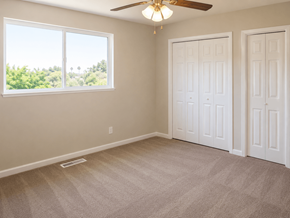 Pittsburg apartment for rent - A room with a carpeted floor, two doors, and a window with a view of trees.