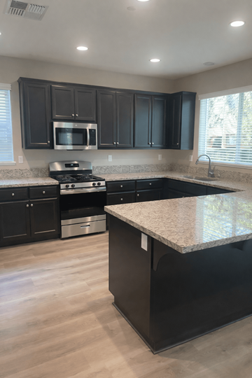 Chico house for rent - A kitchen with black cabinets and a granite countertop.