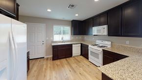 Pittsburg apartment for rent - A kitchen with white appliances and dark brown cabinets.