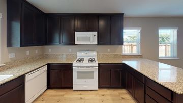 Pittsburg apartment for rent - A kitchen with dark brown cabinets and a white stove top oven.