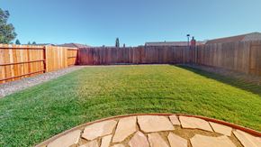 Suisun City house for rent - A backyard with a wooden fence and a stone pathway.