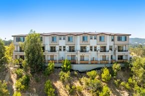 Martinez townhouse for rent - A large, multi-story building with a balcony on the second floor is surrounded by trees.