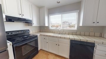 Pittsburg apartment for rent - A kitchen with white cabinets and black appliances.