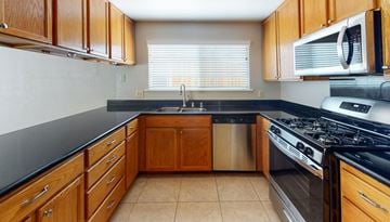 Vacaville apartment for rent - A kitchen with wooden cabinets and a black countertop.