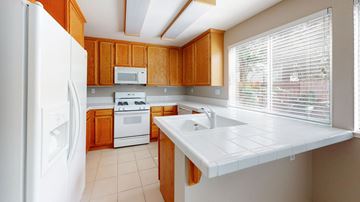 Vacaville apartment for rent - A kitchen with a white refrigerator, white countertop, and wooden cabinets.