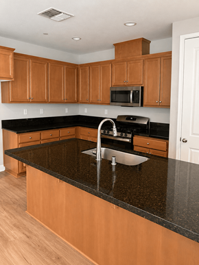 Chico house for rent - A kitchen with wooden cabinets and a black granite countertop.
