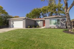 Pittsburg apartment for rent - A house with a grey roof and a red door is surrounded by a green lawn.