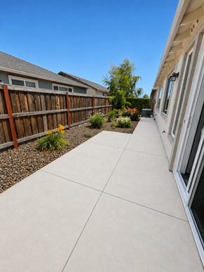 Chico house for rent - A concrete walkway leads between two houses with a wooden fence and shrubbery in the background.