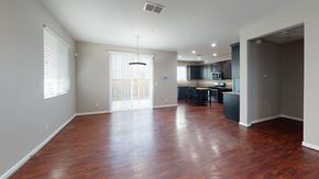 Suisun City apartment for rent - A spacious room with wooden floors and a kitchen area in the background.