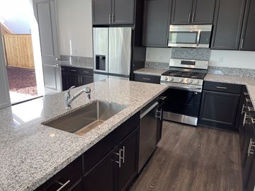 Napa house for rent - A kitchen with black cabinets and a granite countertop.