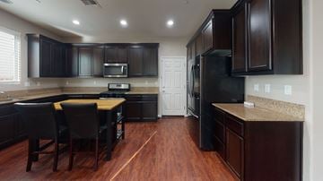 Suisun City apartment for rent - A kitchen with dark wood cabinets and a black refrigerator.