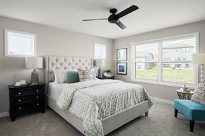 Rochester apartment for rent - A bedroom with a large bed, a ceiling fan, and a window with blinds.