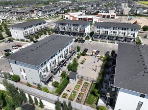Okotoks apartment for rent - A view of a residential area with apartment buildings and a parking lot.