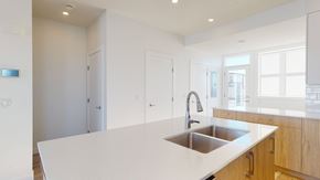 Okotoks apartment for rent - A modern kitchen with a white countertop and a stainless steel sink.