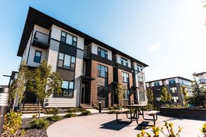 Okotoks apartment for rent - A modern apartment complex with a courtyard and seating area.