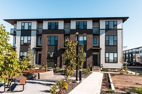 Okotoks apartment for rent - A modern apartment building with a courtyard and benches.